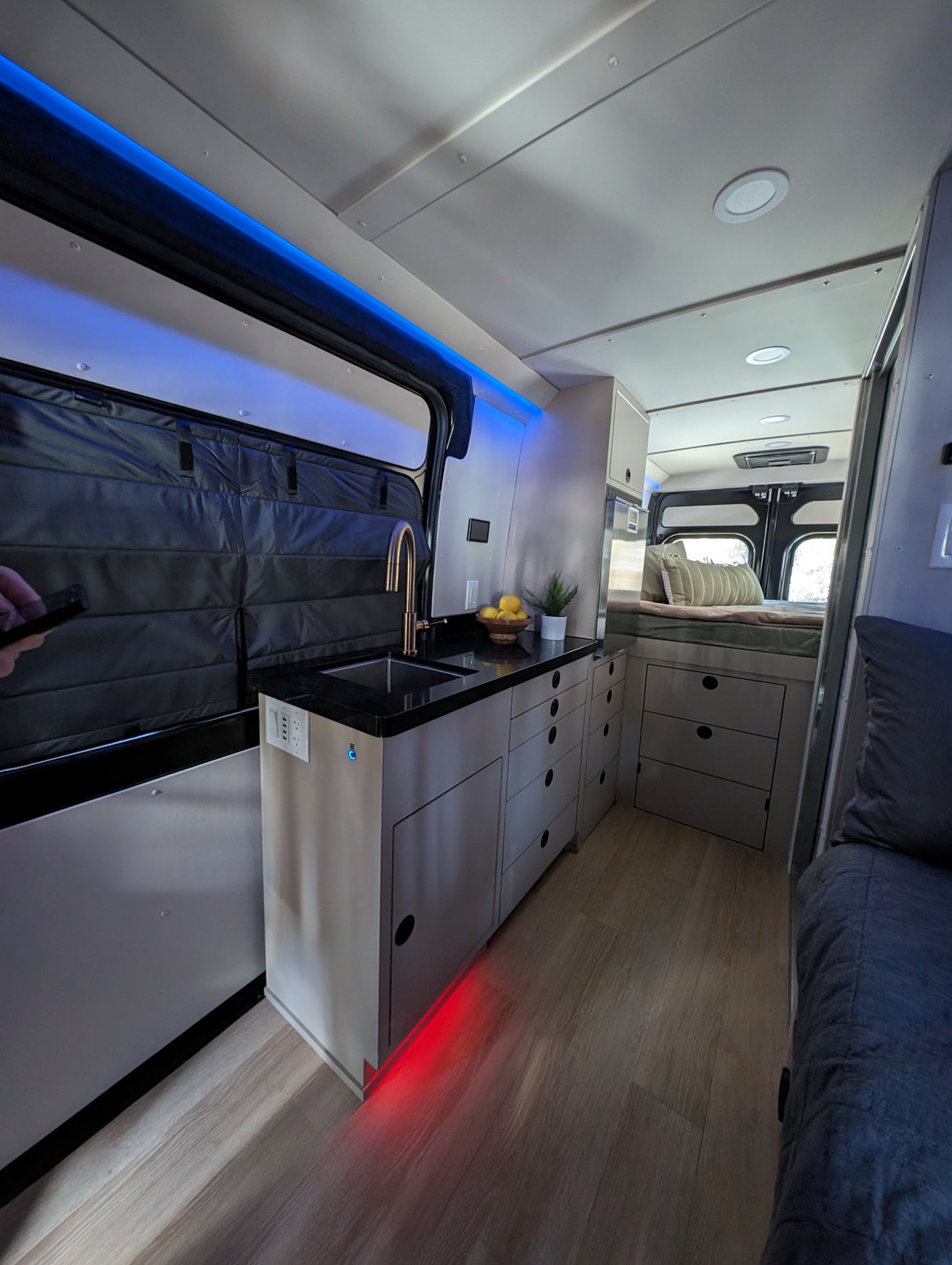 RV rental interior: modern kitchenette with sink, bed, and ambient blue/red lighting. Compact, functional design.