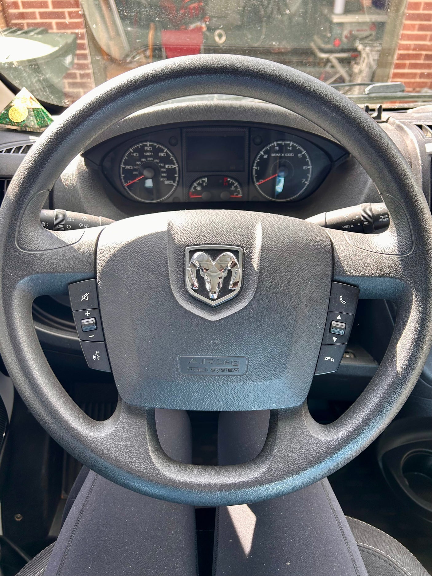 Inside an RV rental, a driver's view shows a steering wheel with a Ram logo, dashboard gauges, and controls.