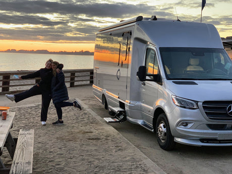 Friends enjoying a beautiful beachfront sunset beside their Airstream rv rental. Perfect travel memories!