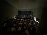 Cozy RV rental sleeping area at night. Dimly lit camper van interior with floral bedding & back window outlines visible.