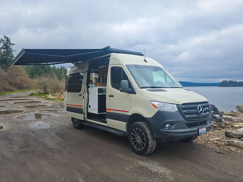 Spacious RV rental van with awning extended, parked on a muddy road by the water. Interior visible for comfortable van life. — photo 4