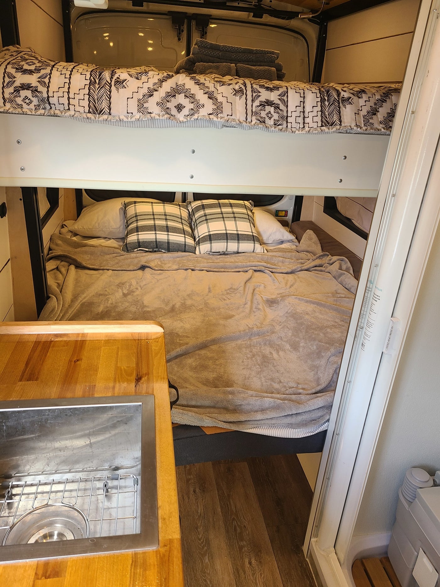 RV rental interior with cozy bunk beds, a compact kitchen sink, and a portable toilet for comfortable trips. — photo 8