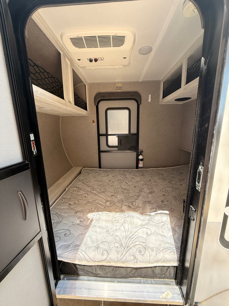 View into an RV rental bedroom with a queen-sized bed, ceiling AC unit, and overhead storage nets for comfortable travel. — photo 4