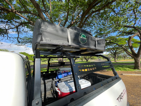 White pickup truck with rooftop tent & overland gear, ready for adventure like an RV rental.