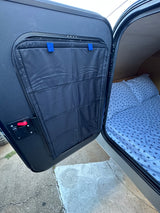 Open door of an RV rental camper showing interior storage pockets and turtle-patterned bedding.