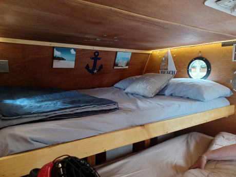 Cozy RV rental bunk beds feature nautical decor, warm lights, and a porthole window. Perfect for your travel comfort.