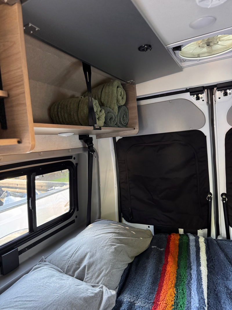 Cozy RV rental interior with a comfortable bed, colorful blanket, handy overhead storage, and window view. — photo 14