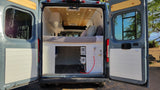 Explore comfort in this custom camper van for rv rental, showing its interior layout with bed, storage, and outdoor shower.