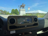 Inside an RV rental: dashboard with navigation showing Forest Park, an equestrian statue, and a large tent visible outside.