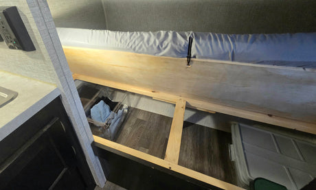 RV rental: Under-bunk storage area featuring wooden support frame, clear bins, and a larger container for organized travel gear.