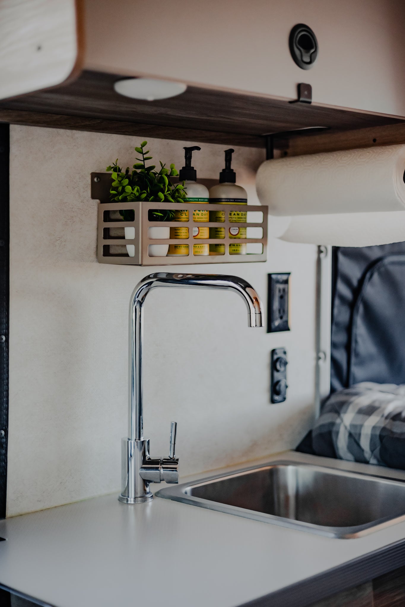 This RV rental offers a well-equipped compact kitchen: stainless steel sink, modern faucet, and organized wall storage for essentials.