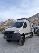 White off-road RV rental van in a rocky desert camp. Ideal for adventure travel and exploring remote landscapes.