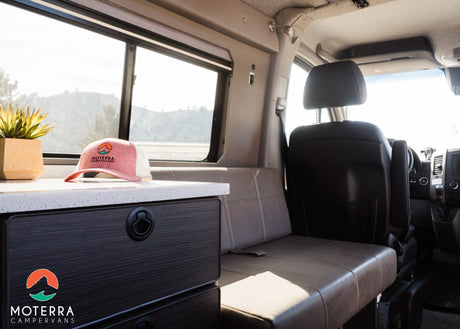  a pull-out table with stove and berries.|Inside an RV rental: a dark wood-look Isotherm fridge beneath a speckled countertop