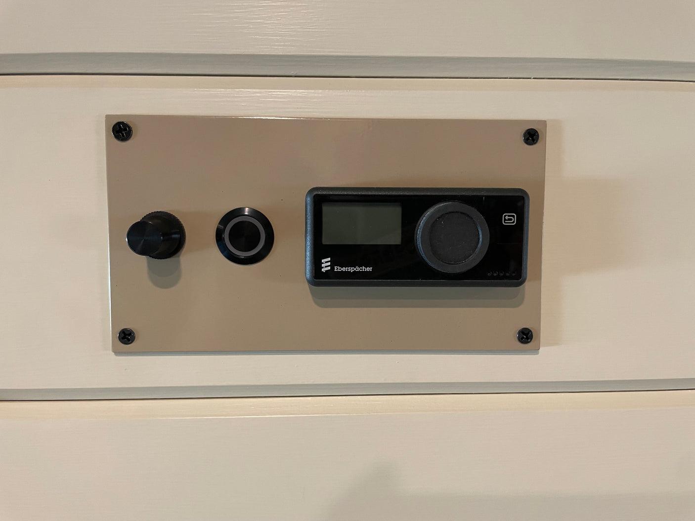Beige control panel for an Eberspächer heater in an RV rental, showing a digital display, a large knob, and a small button.