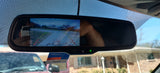 A car's rearview mirror with backup camera display and NTTA sticker. This safety feature is essential for parking, especially with an RV rental.