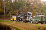 Ready for adventure, these off-road vehicles with rooftop tents line a pond in autumn. Consider an RV rental for your next overlanding trip.