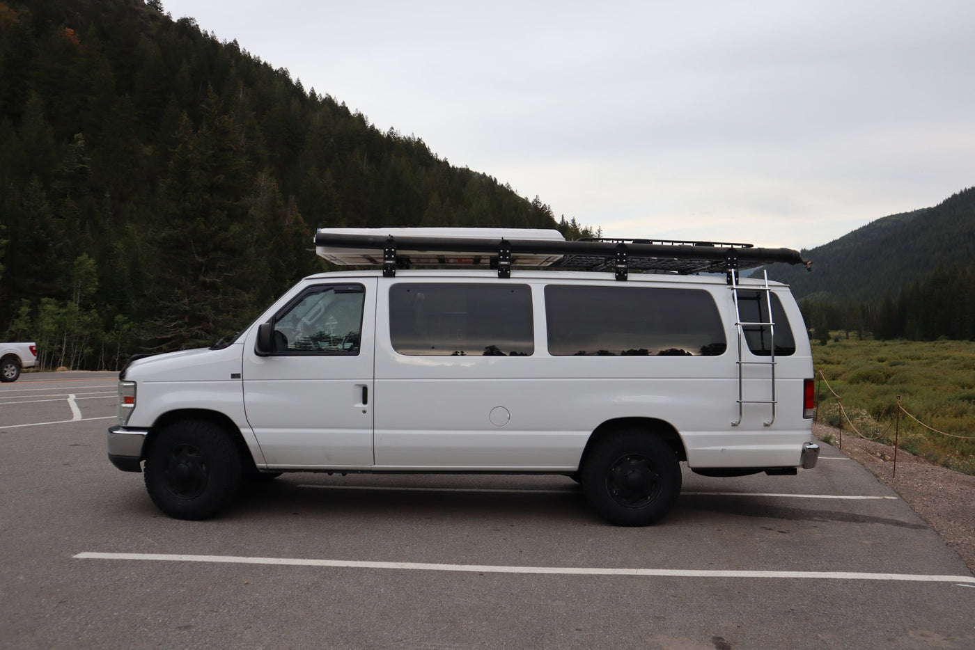 White adventure-ready van, with roof rack & ladder, parked in scenic mountains. Perfect rv rental for nature trips. — photo 2
