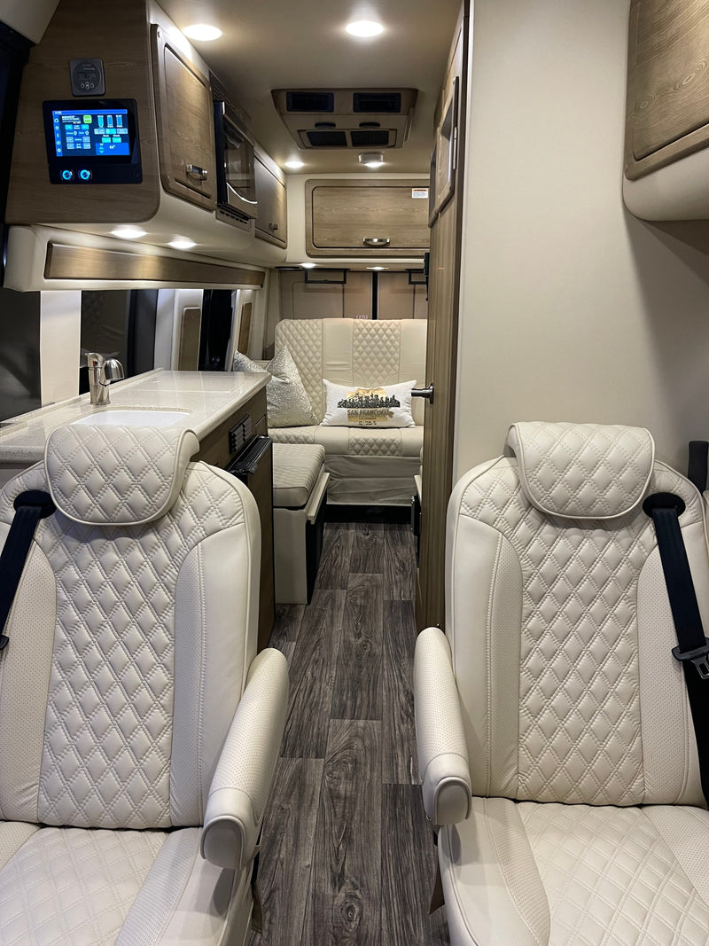Luxury RV rental interior: white quilted captain's chairs, modern kitchen, and comfortable lounge area. — photo 3