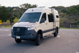 This Mercedes Sprinter camper van rv rental, customized with a map graphic & roof ladder, is parked for adventure.