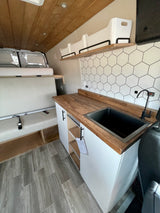 RV rental with a modern interior: compact kitchen, wood counters, hexagonal backsplash, black sink, and versatile bench seating.