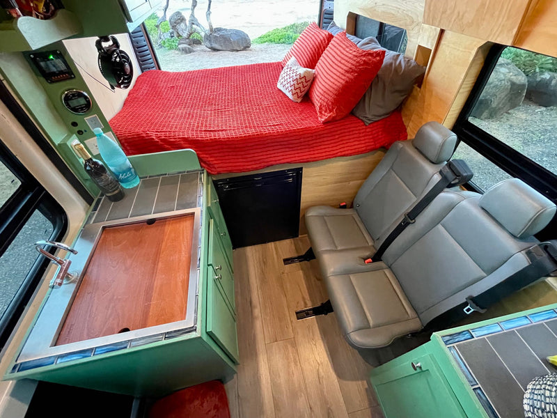  facing a beautiful blue beach with ocean under a clear sky.|Inside this RV rental: a compact kitchen — photo 2