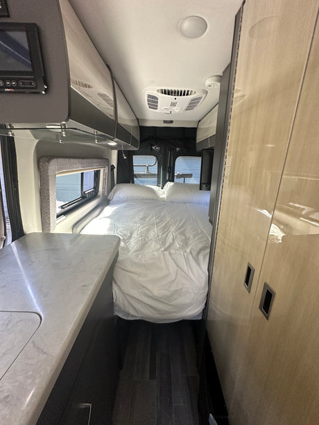 Comfortable rv rental interior: full bed, modern kitchen counter, and overhead storage, perfect for adventures.