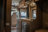 Inside a sleek rv rental: a modern kitchen with sink, fridge, & wood cabinets, offering comfort & convenience on the road.