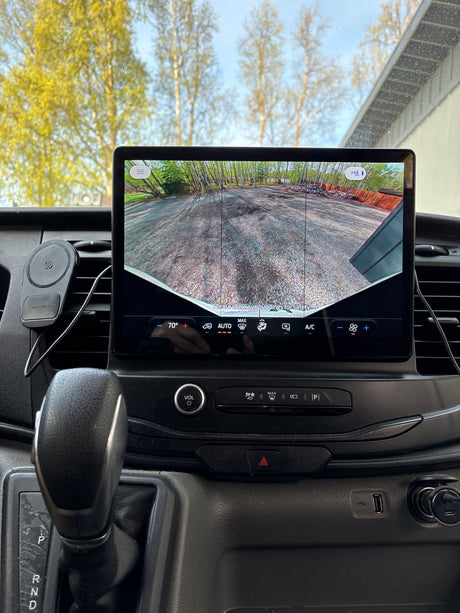 Inside an **rv rental** van, the large display shows the backup camera view with climate controls and the gear shift.