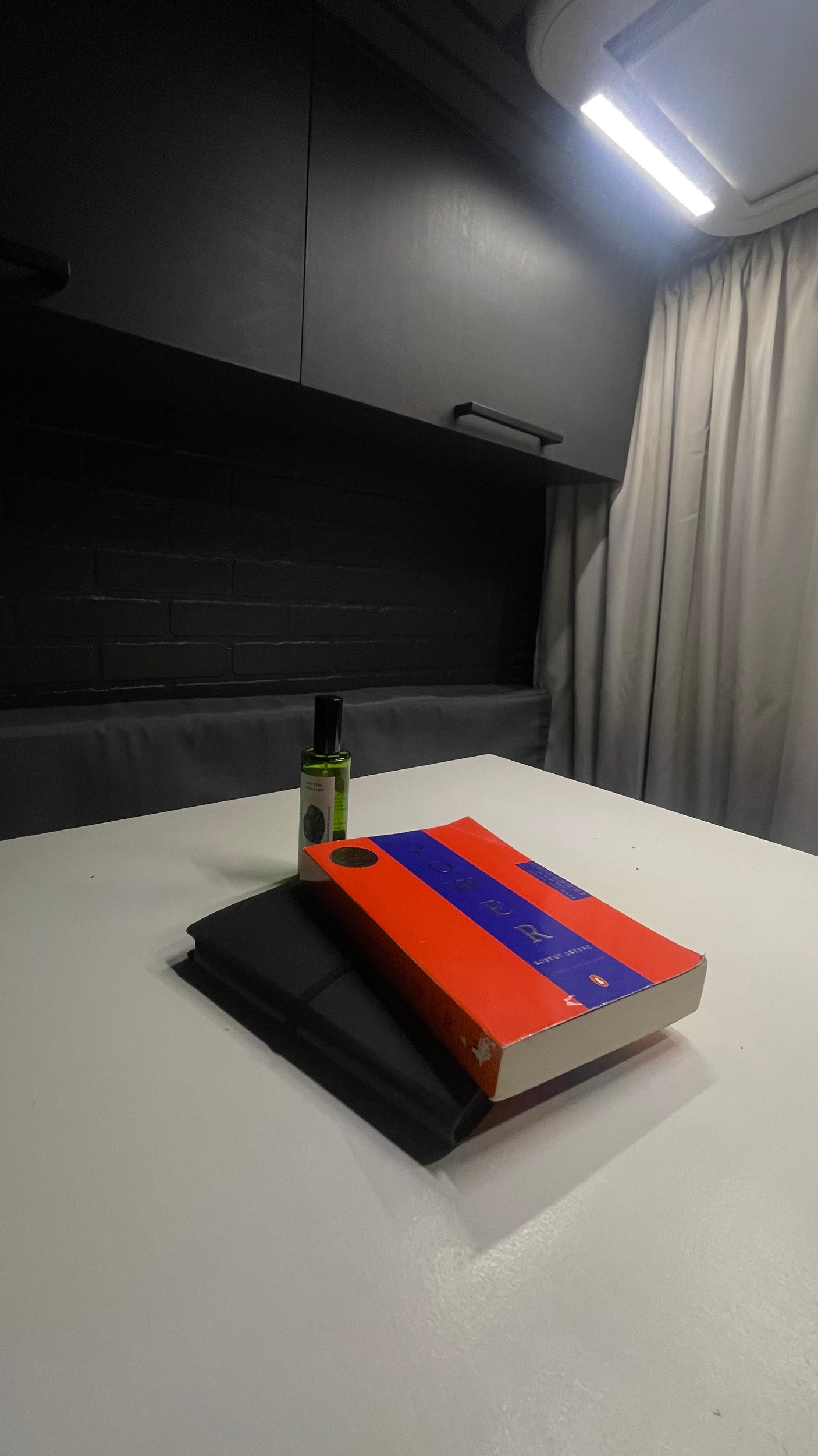 Cozy RV rental interior with a book, notebook, and bottle on a white table under bright lights.
