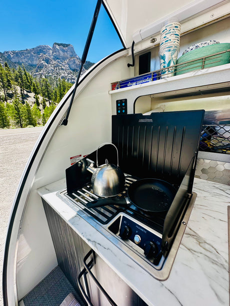 RV rental cooking setup: Kettle & pan on a Dometic stove with stunning mountain views. Ready for adventure!