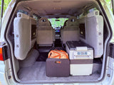 RV rental van's cargo area: Portable fridge, bags, and rearranged seats, ready for a camping trip.