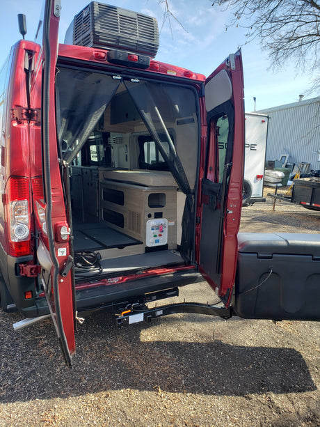 Red RV rental camper van with open back doors, showing interior living space, roof AC, and rear hitch/cargo box. Ready for adventure.