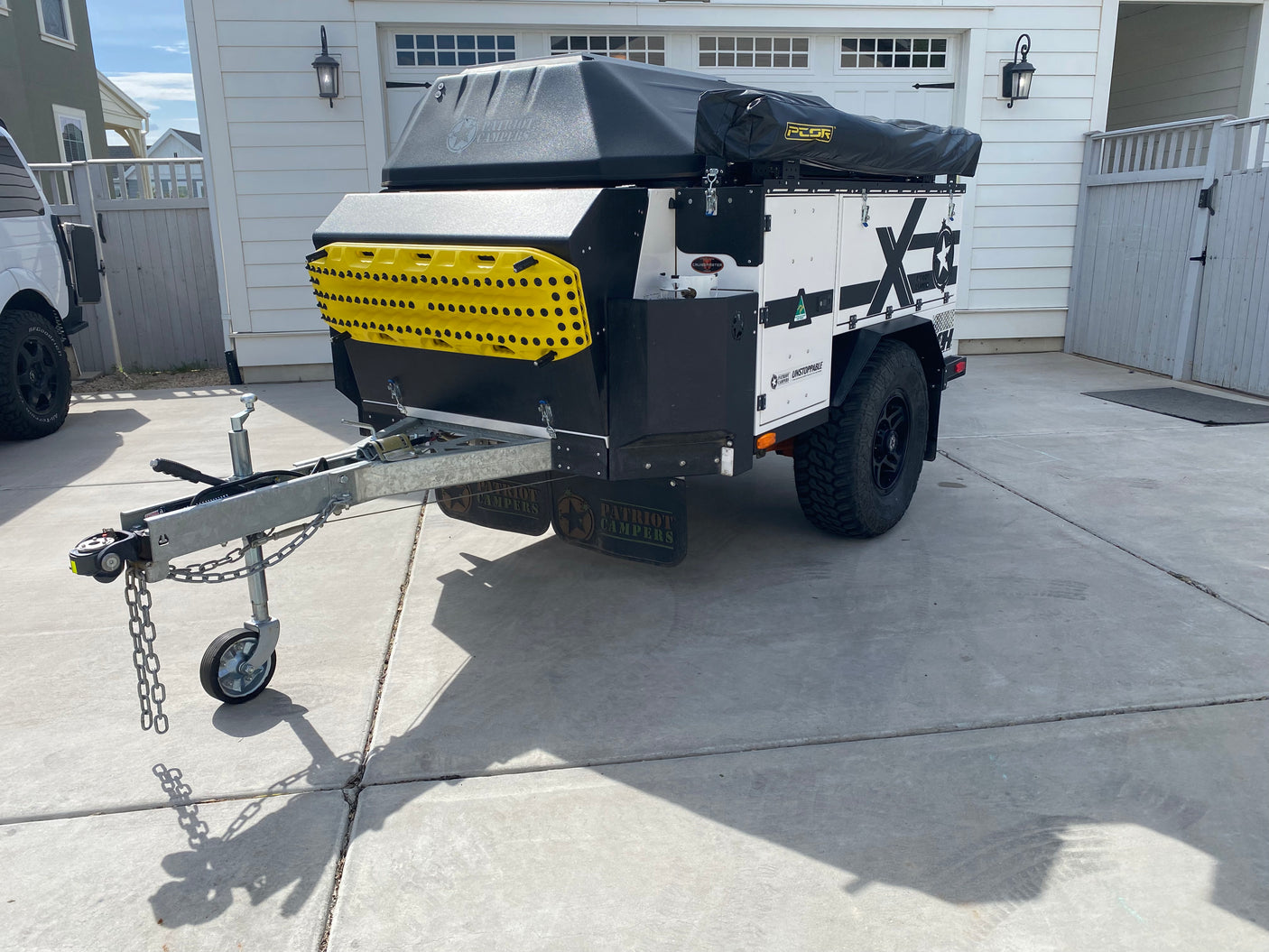 This black & white overland camper trailer with yellow recovery boards is ideal for RV rental adventures.