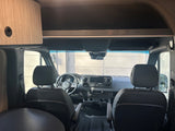 Spacious rv rental interior: Looking into the modern cockpit with front seats, steering wheel, and dashboard.