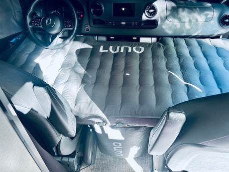 Interior of an RV rental van with a LUNO air mattress converting front seats into a bed. Ideal for comfortable van camping.