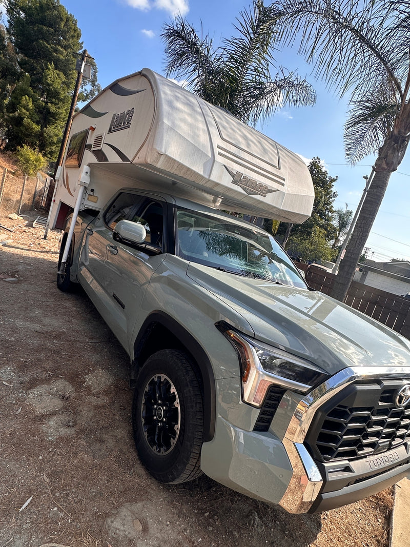  parked on a dirt path. Consider an rv rental.|A light green Toyota Tundra pickup truck with a Lance truck camper mounted on its bed — photo 13