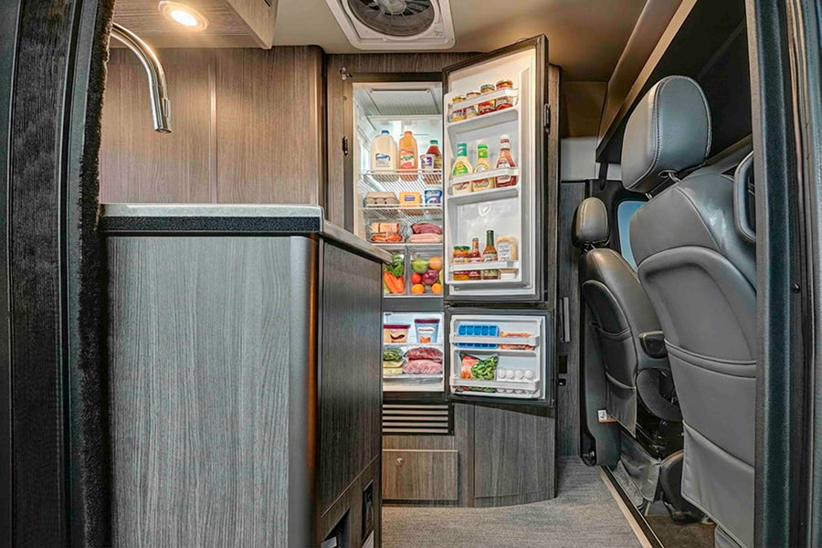 Explore a well-stocked rv rental kitchen: open fridge, sink, and front cabin seats in this modern interior.