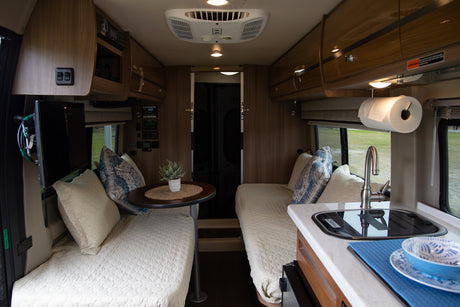 This RV rental interior features a versatile living space with cozy beds, a compact kitchen, and convenient amenities.