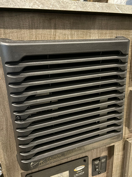 RV rental interior: A wall-mounted heater/converter vent with caution warning, above a Go Power control panel.