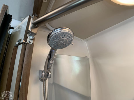 Modern RV rental shower with chrome fixtures & folding door. Clean and compact for your adventure.