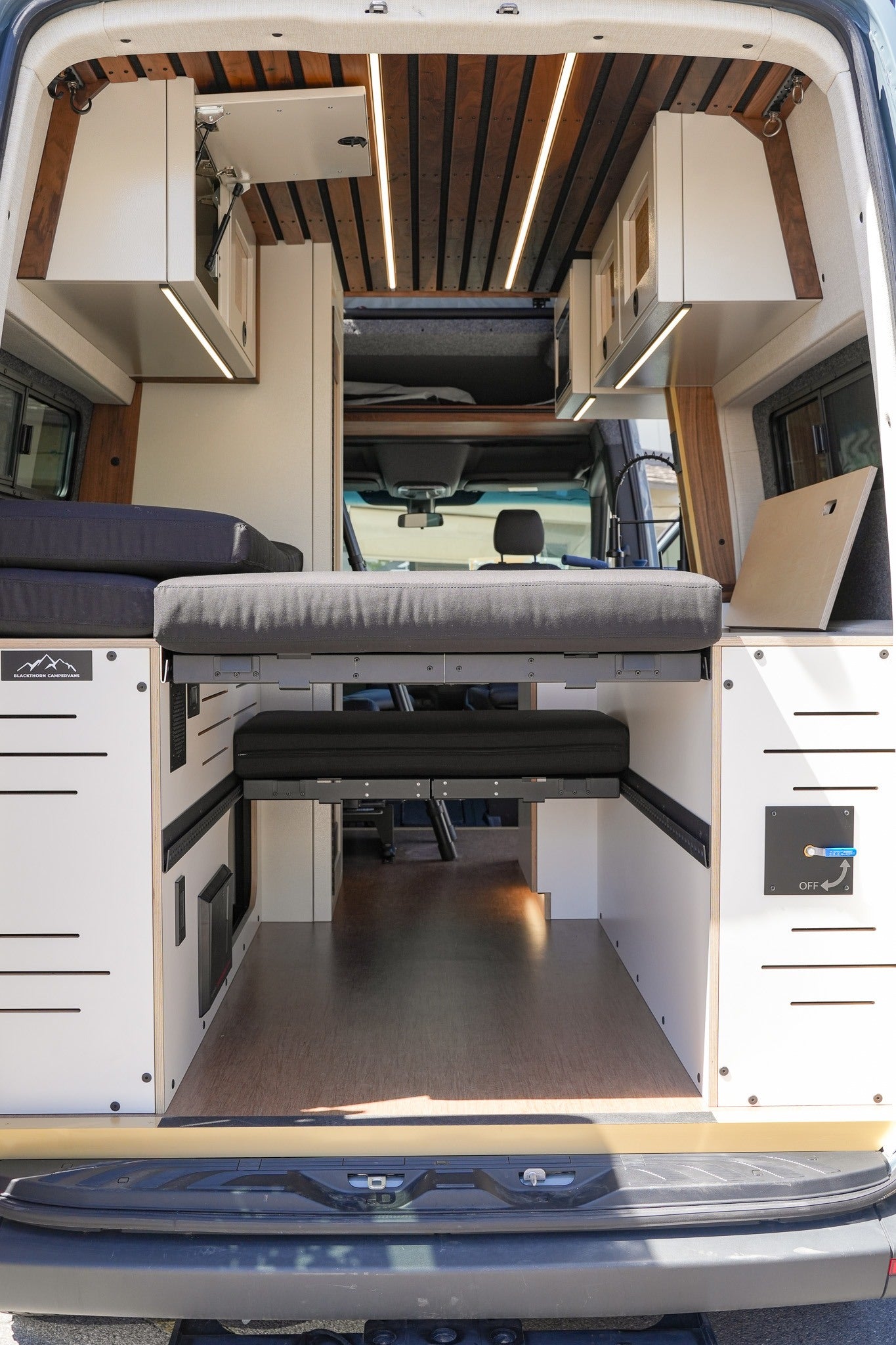 Step into this custom RV rental, featuring a versatile modular bed, overhead storage, and warm ambient lighting.