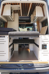 Step into this custom RV rental, featuring a versatile modular bed, overhead storage, and warm ambient lighting.