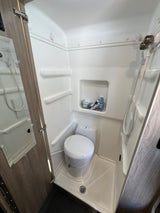 Compact RV rental wet bath with toilet, shower, and mirror, perfect for small spaces.