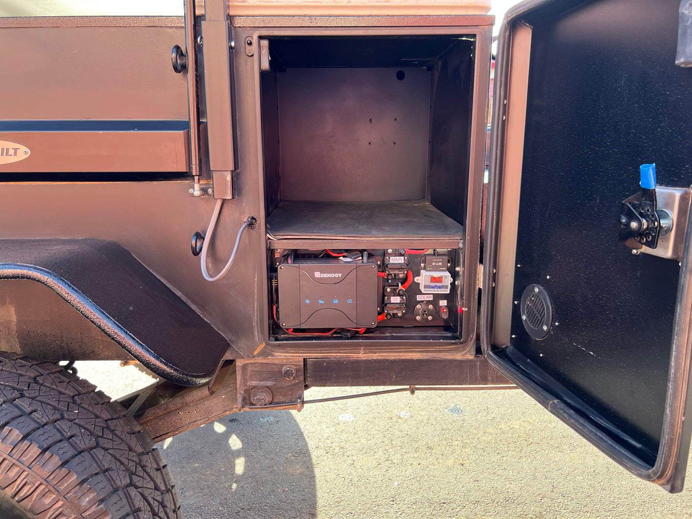 RV rental power hub: Inside a camper's utility box with Renogy battery/solar management and electrical controls.