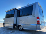 Silver Airstream RV rental parked on a sunny sandy shore, side open. Perfect for outdoor adventures and scenic travel.