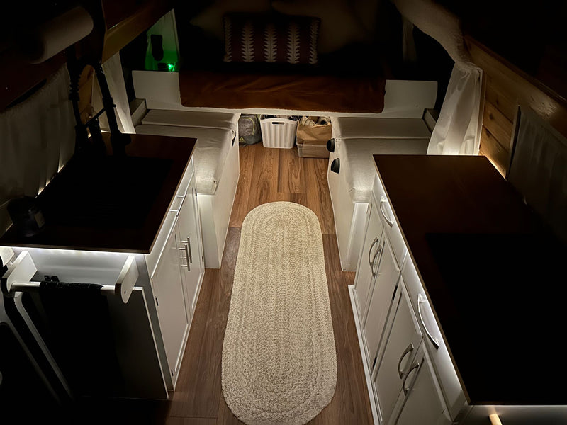  and a "WELCOME" sign. Recessed lights illuminate the space.|Cozy RV rental interior with wood-paneled walls/ceiling — photo 14