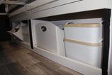 RV rental storage: Smart under-bed organization with white bins and baskets on wood flooring.