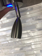 RV rental: A finger presses a blue illuminated touch LED light mounted above a stylish subway tile backsplash inside an RV.