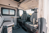 RV rental interior showcasing front swivel seats, a cozy dining table, and large window, perfect for your next adventure.