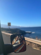 Side mirror selfie on a stunning coastal road trip with our RV rental. Beautiful ocean views ahead!
